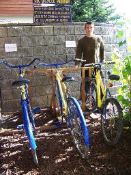 Lucas Wilcox poses with some of the gold-and-blue bikes available for student, faculty and staff use at the parking lot entrance of Kachemak Bay Campus, Kenai Peninsula College-University of Alaska Anchorage. (Photo by McKibben Jackinsky/Homer News)